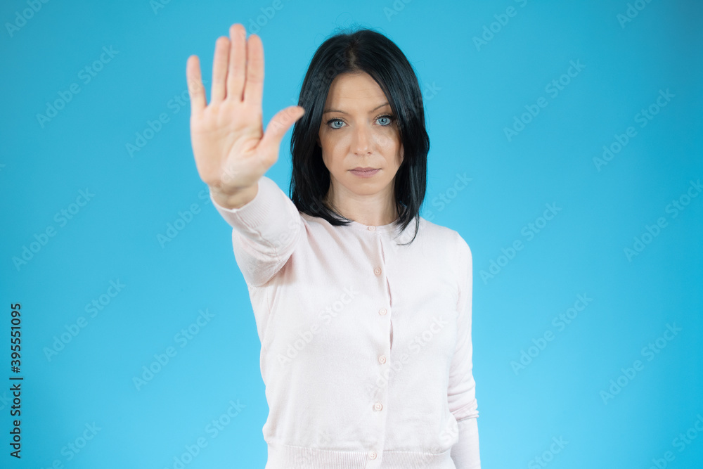 Young brunette woman with blue eyes wearing casual sweater over isolated blue background doing stop gesture with hands palms, angry and frustration expression Young brunette woman with blue eyes wearing casual sweater over isolated blue background doing stop gesture with hands palms, angry and frustration expression