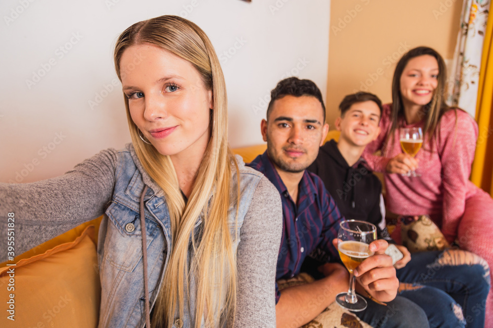 Obraz premium Portrait of happy young people having a selfie while sitting at home with beer - Friends having fun in the living room and taking selfie -