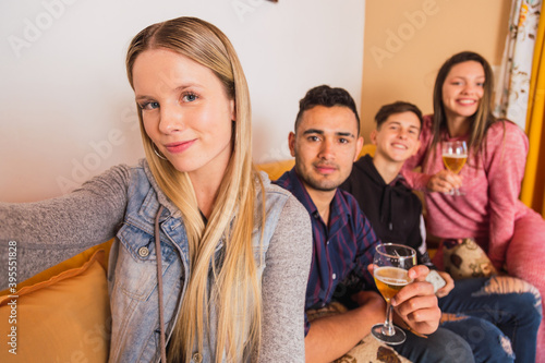 Portrait of happy young people having a selfie while sitting at home with beer - Friends having fun in the living room and taking selfie -