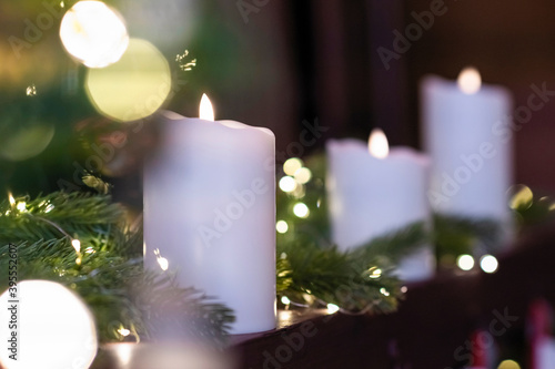 Selective focus of burning candle in Christmas decoration with light bokeh. Close up