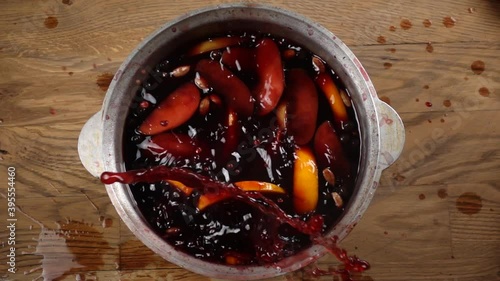 Slow motion of falling orange slice in mulled wine that preparing in big old metal kettle, above laytop view photo