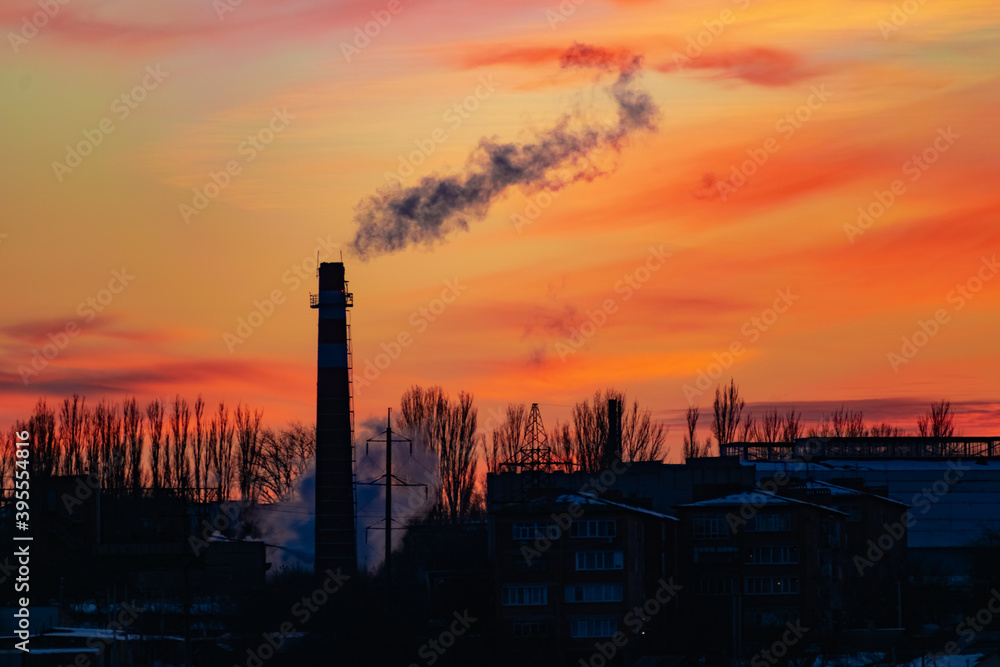 High and wide chimney, a pipe with a large amount of smoke and substances released into the atmosphere. Part of a factory or enterprise that pollutes the environment in a snowy and frosty winter near 