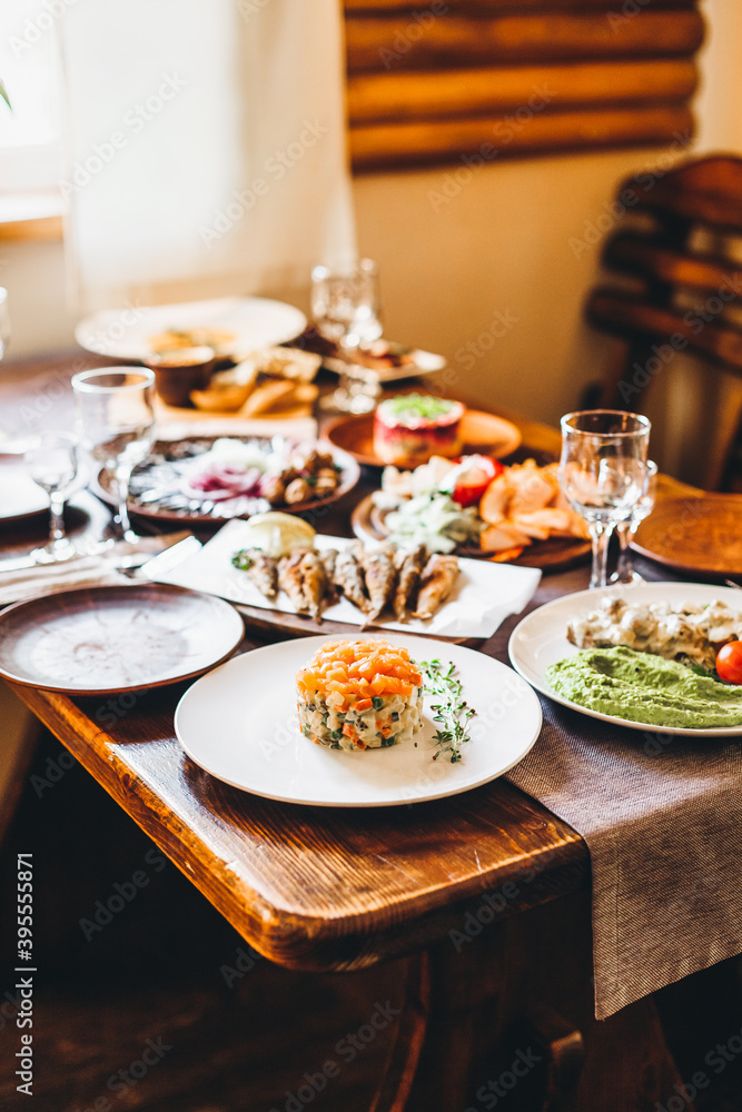traditional russian herring salad under a fur coat and olives on a wooden table next to other festive dishes