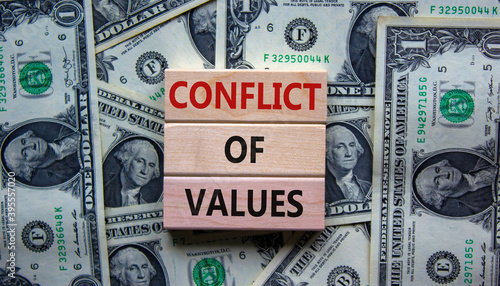 Conflict of values. Wooden blocks with words 'conflict of values'. Beautiful background from dollar bills. Copy space. Business and conflict of values concept.