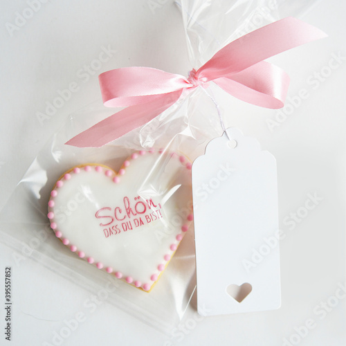 A biscuit with a saying packed in a cellophane bag with a pink bow