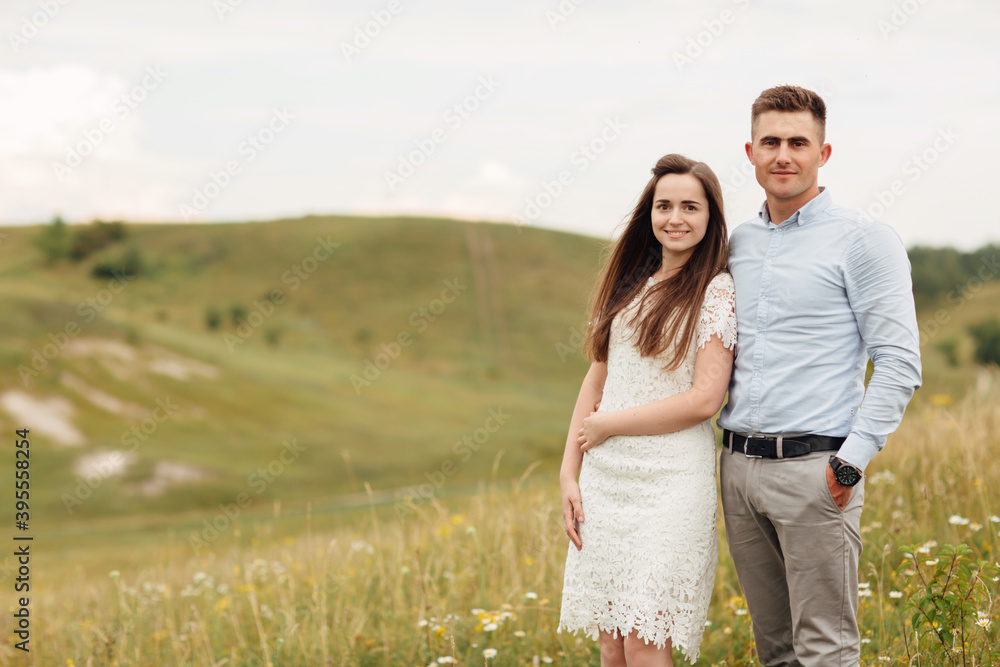 Young beautiful couple is hugging in the field in summer. woman with long hair and man with stylish haircut Young beautiful couple is hugging in the field in summer. woman with long hair and man with stylish haircut