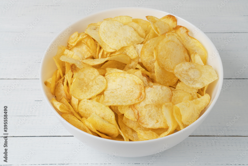 Bowl of natural potato chips on white wooden table. Bowl of natural potato chips on white wooden table.