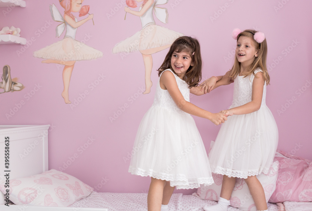Little girls, sisters, twins standing on the bed in their lovely pink room Little girls, sisters, twins standing on the bed in their lovely pink room