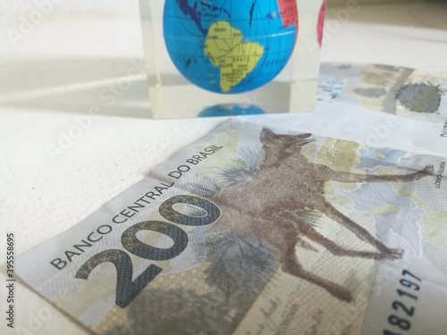 Brazilian 200 reais bank notes with the world globe on top. Maned Wolf on the currency. Two hundred real from Brazil. Close up of Brazilian money. New notes on moment of economic crisis on the planet. photo