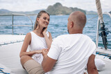 Young beautiful married couple kissing on the yacht on vacation. Caucasian woman with long hair and bald man in the Andaman sea. Phuket.