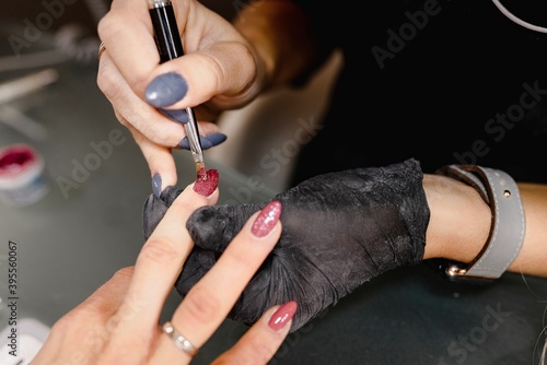 Close up unrecognizable hands. Manicurist applying nail polish on client s fingernails. Professional  beauty concept.