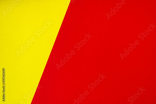 Beautiful background of two unequal parts yellow and red. Sheets of blank yellow and red paper with fine texture separated by a sloping border.