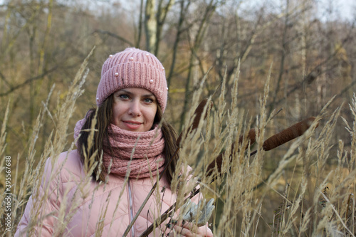 A girl in autumn clothes with a bouquet of reeds in her hands. Walking in nature in the park. Close-up shot.