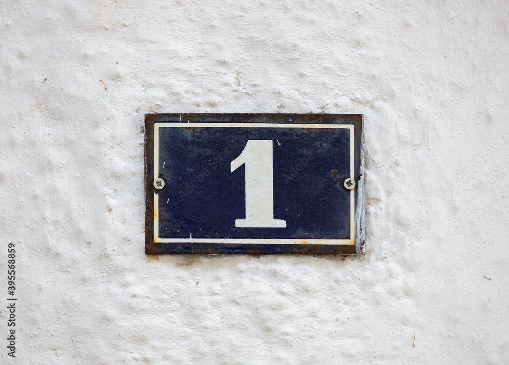 Street number one. House address metal sign on whitewashed wall. Street number one. House address metal sign on whitewashed wall.