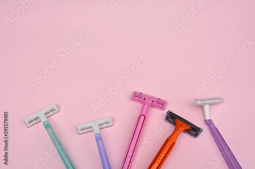 Multi-colored female disposable razors on a pink background with space for design and text.