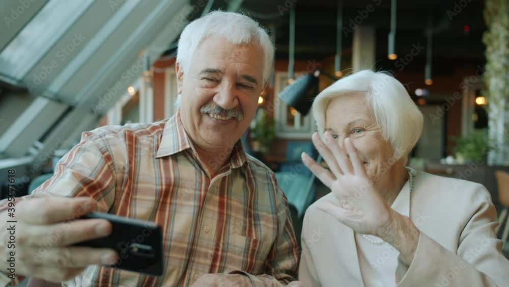 Happy retired people man and woman are taking selfie having fun talking and smiling using smartphone camera in cafe. People and devices concept. Happy retired people man and woman are taking selfie having fun talking and smiling using smartphone camera in cafe. People and devices concept.