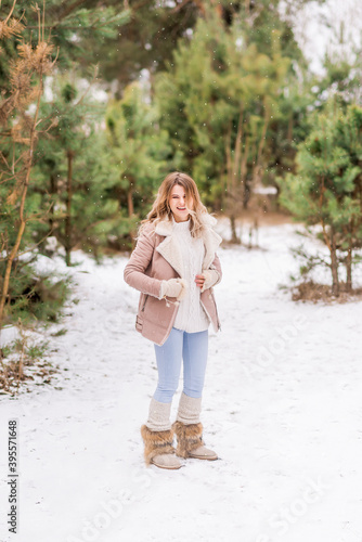 Beautiful young woman in jeans and pink jacket laughing in the winter forest © Марина Шавловская