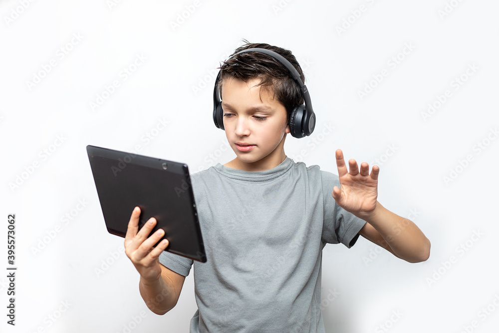 Teenage caucasian boy using tablet with headphones. Technology e-learning concept. Isolated white background. Digital communication Teenage caucasian boy using tablet with headphones. Technology e-learning concept. Isolated white background. Digital communication