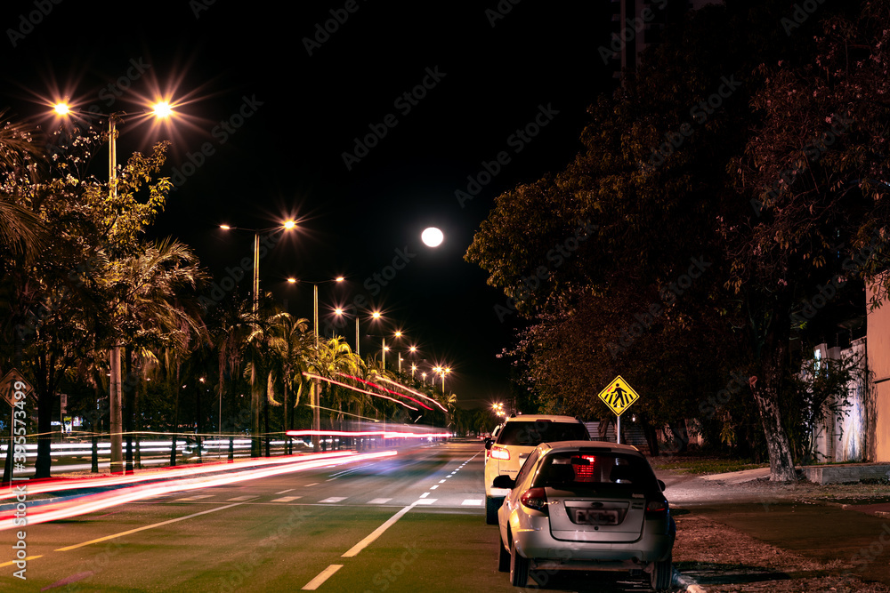 Lua em longa exposição com carros passando em uma avenida na cidade de Palmas TO