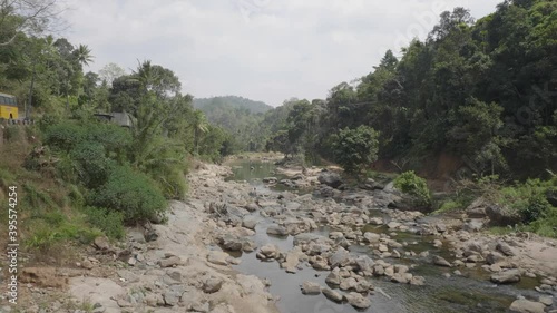 Nallathanni river in munnar hills in the drier season of the year with dense forest in the background and a yellow bus parked on the side of the road photo