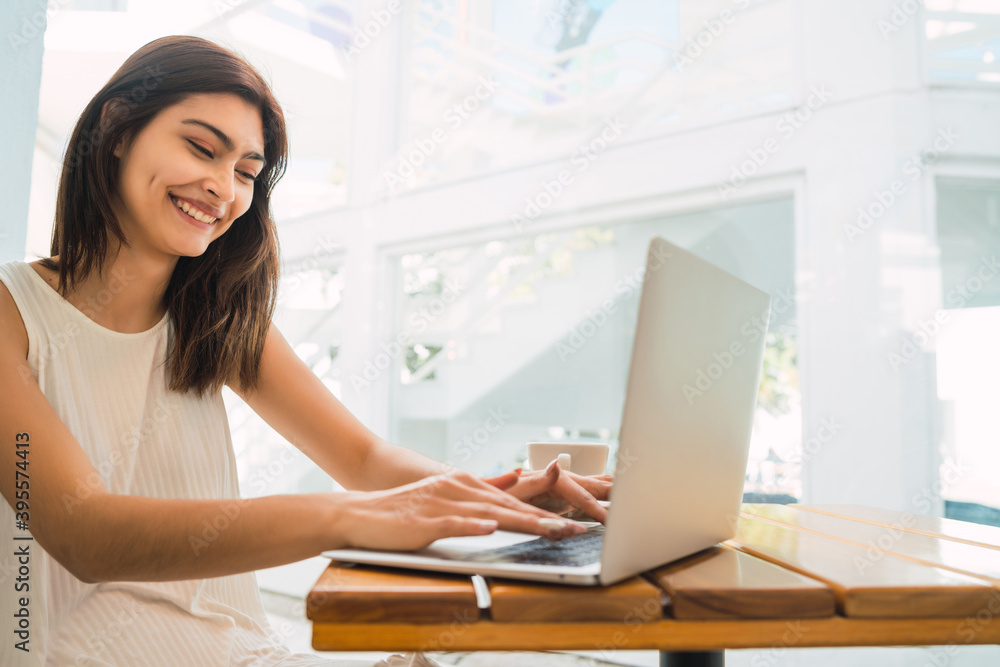 Fototapeta premium Young woman using laptop at coffee shop.