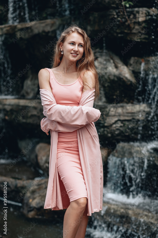 Young woman in pink dress posing near blurred waterfall. Kuala Lumpur. Malaysia. Young woman in pink dress posing near blurred waterfall. Kuala Lumpur. Malaysia.
