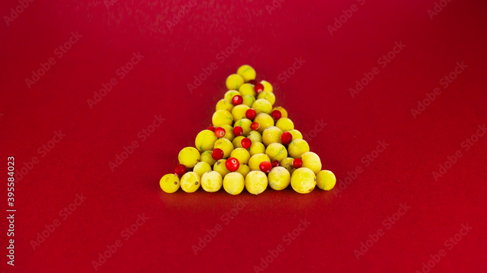 Obraz premium christmas tree made from gooseberries and cranberries on red background