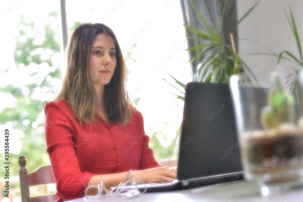 Young woman working at home and attending a meeting on her laptop. Young woman working at home and attending a meeting on her laptop.