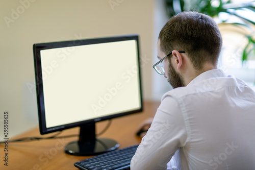 A man with glasses sits at the monitor looking at a blank display