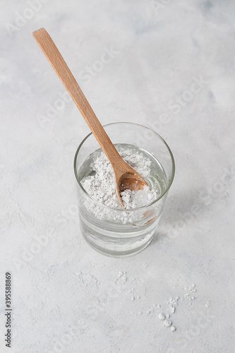 Close-up collagen powder in a spoon with a glass of water , on concrete background.