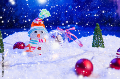 Christmas background with Christmas balls on snow over fir-tree, night sky and moon. Shallow depth of field. Christmas background. Fairy tale. Artificial magic dreamy world.