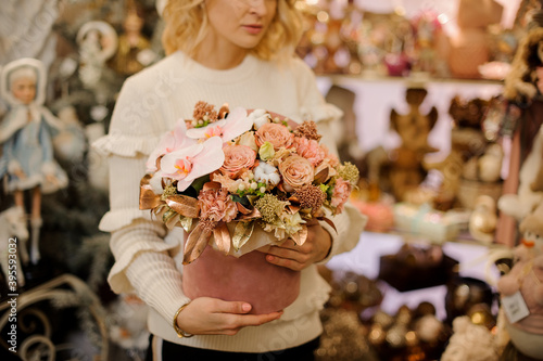 luxury flower arrangement of orchids and roses in box in hands of blonde woman