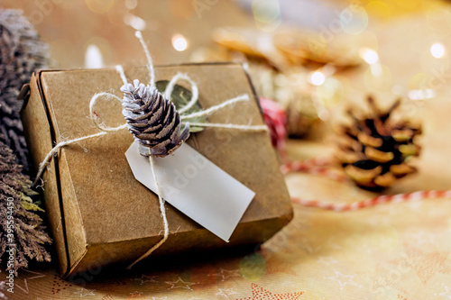 New Year's gift in sustainable gift wrap. Cardboard box tied with twine and decorated with a lump. Eco-friendly Christmas gift wrapping, copy space