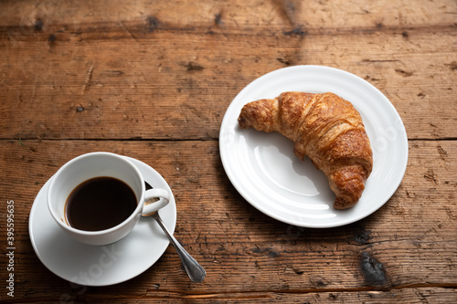 Fototapeta Naklejka Na Ścianę i Meble -  breakfast on the wooden table with a croissant and a cup of coffee.