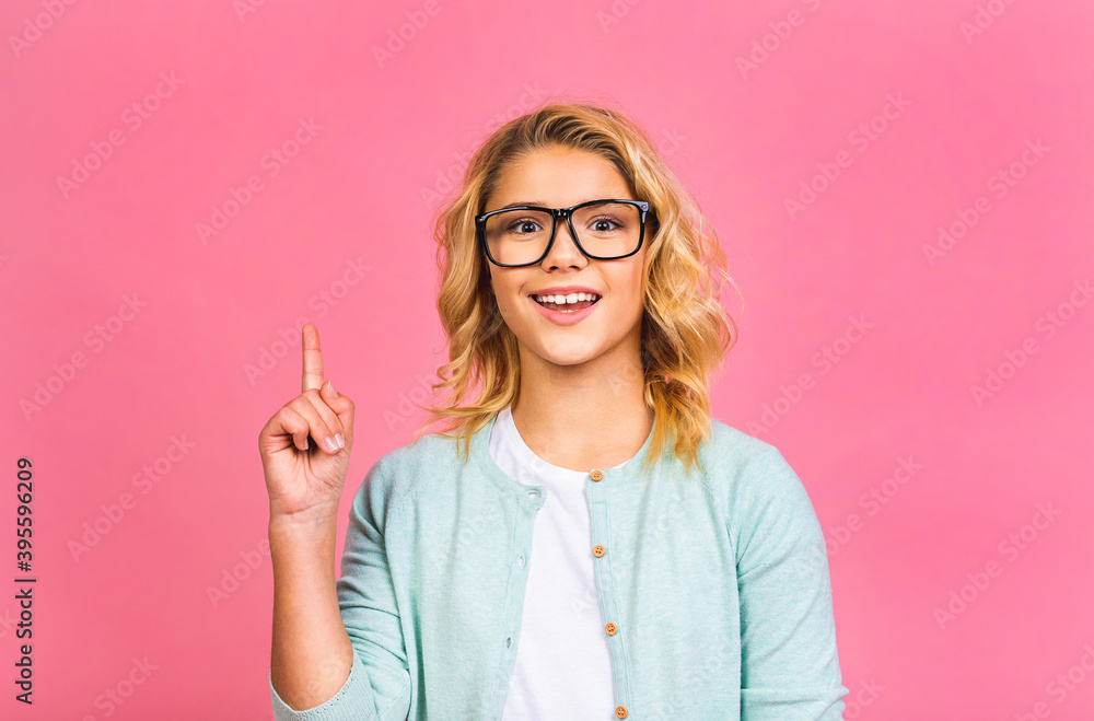 Smiling little kid girl 12-13 years old in casual isolated on pink background children studio portrait. Childhood lifestyle concept. Mock up copy space. Pointing finger. Smiling little kid girl 12-13 years old in casual isolated on pink background children studio portrait. Childhood lifestyle concept. Mock up copy space. Pointing finger.