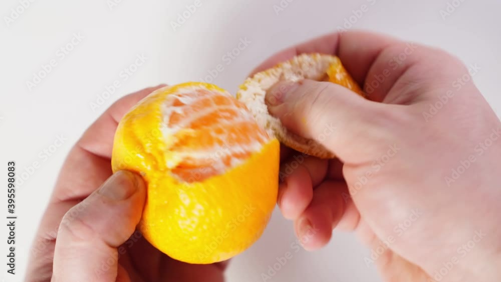 men's hands peel the tangerine and divide it into slices. citrus fruit. symbol of the new year. men's hands peel the tangerine and divide it into slices. citrus fruit. symbol of the new year.