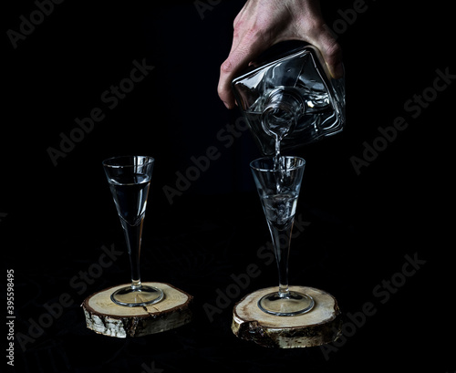 Serving or pouring a glass of an alcoholic drink into a fine glass on a black background