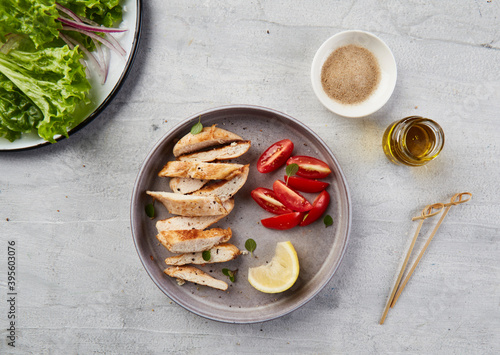 Chicken strips on gray plate with tomato, herbs and lemon. photo