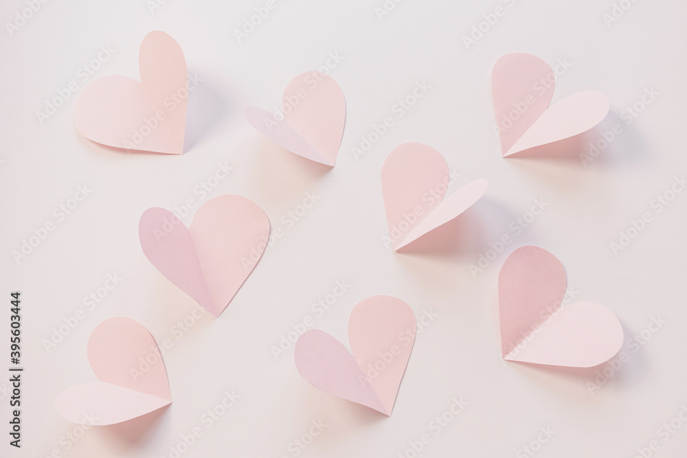 Pink paper hearts on a light pastel background. Concept of romance, love, valentine's day. Minimalism, copy space, paper art.