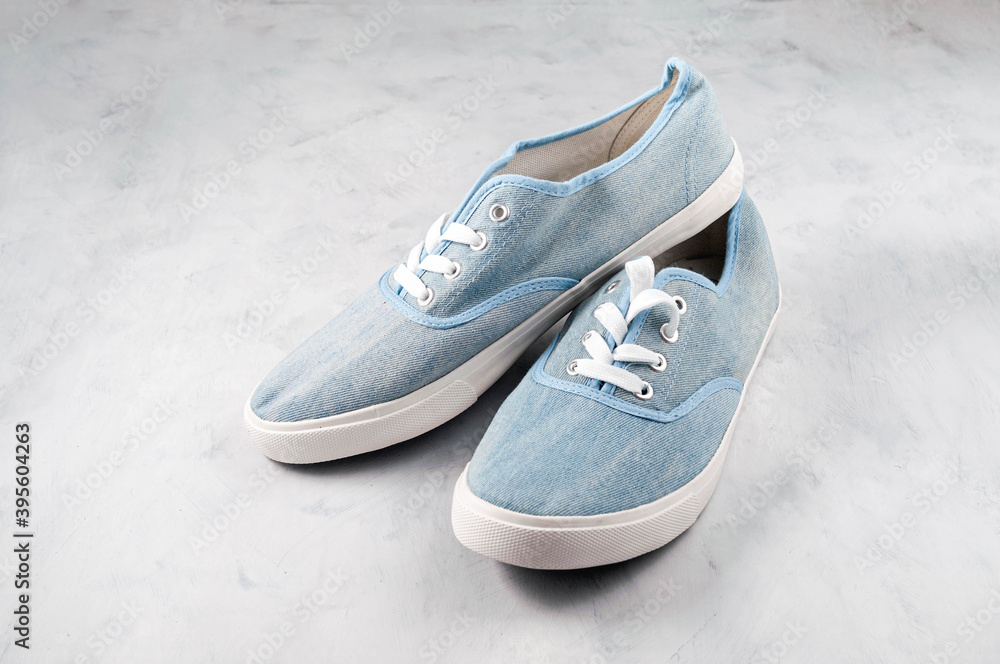 high angle view of pair blue fabric sneakers on grey textured background