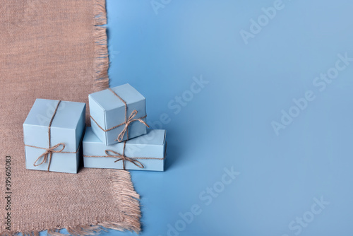 Gift boxes with jute rope on a blue background with burlap.