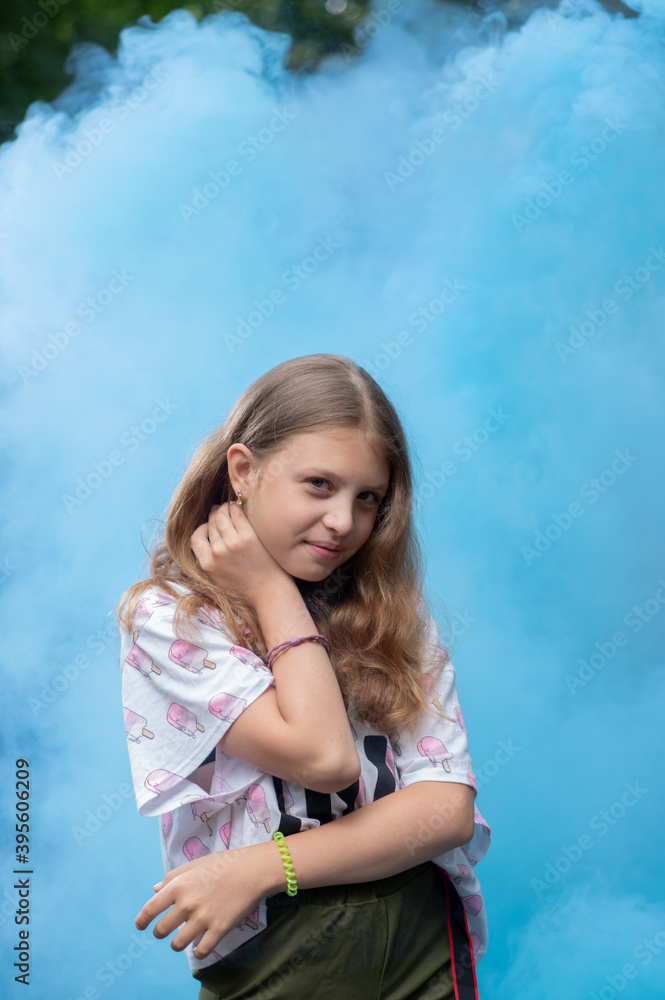 Posing girl on a blue background. Blue smoke on the background of the girl. Portrait of a girl with blue smoke. Posing girl on a blue background. Blue smoke on the background of the girl. Portrait of a girl with blue smoke.