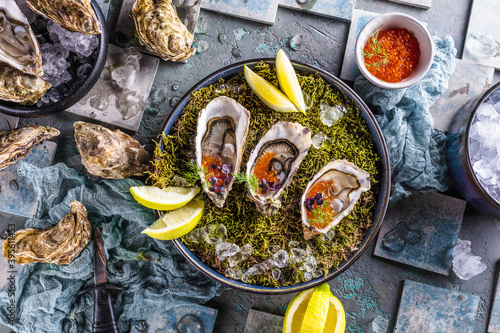 Fototapeta Naklejka Na Ścianę i Meble -  Leckere Austern auf Eis mit Zitrone. Raffiniert mit Kräutern und Lachskaviar.