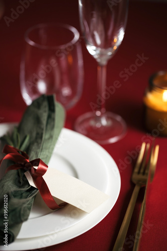 Christmas table setting on red tablecloth with candles. Holiday serving table with golden cutlery.