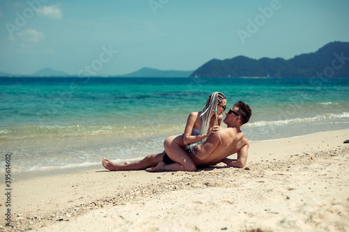 Sensual young couple in swimsuits laying on the sand by the sea over sky and tropical island background. Phuket. Thailand. © Semachkovsky 