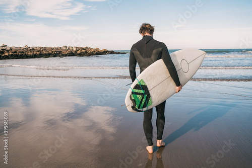 Surfer entering into the water with his surfboard.