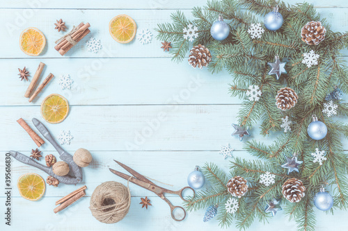 Christmas light blue background, spices and dried fruits, cord and aged scissors for craft. Festive decoration, pine tree branches set, blue silver baubles, snowflakes. Top view, copy space.