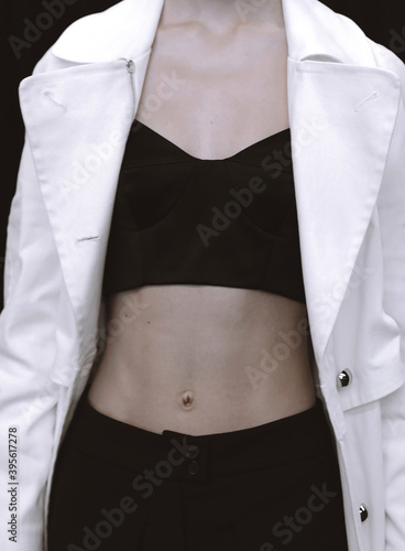 Ccropped female figure in black top and white trench coat. Fashion shot © asauriet