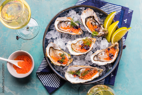 Tasty oysters on ice with lemon. Refined with herbs and salmon caviar.