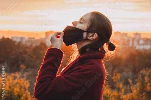 Foto Side view of young woman taking the face mask off for a gulp of fresh air backli